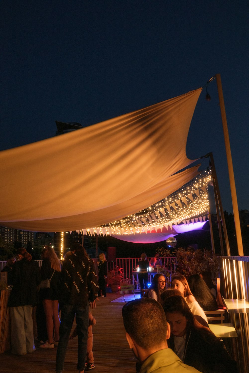 a group of people standing under a canopy at night
