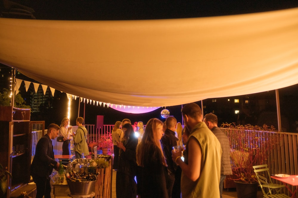 a group of people standing under a tent at night