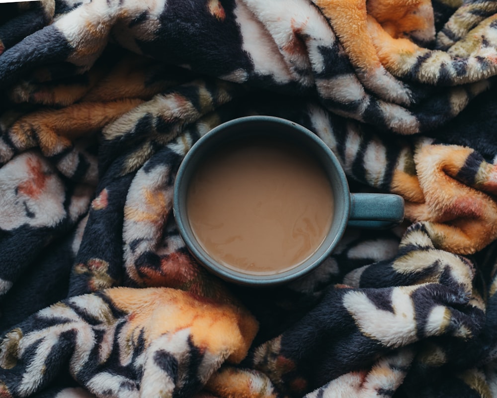 a cup of coffee sitting on top of a blanket