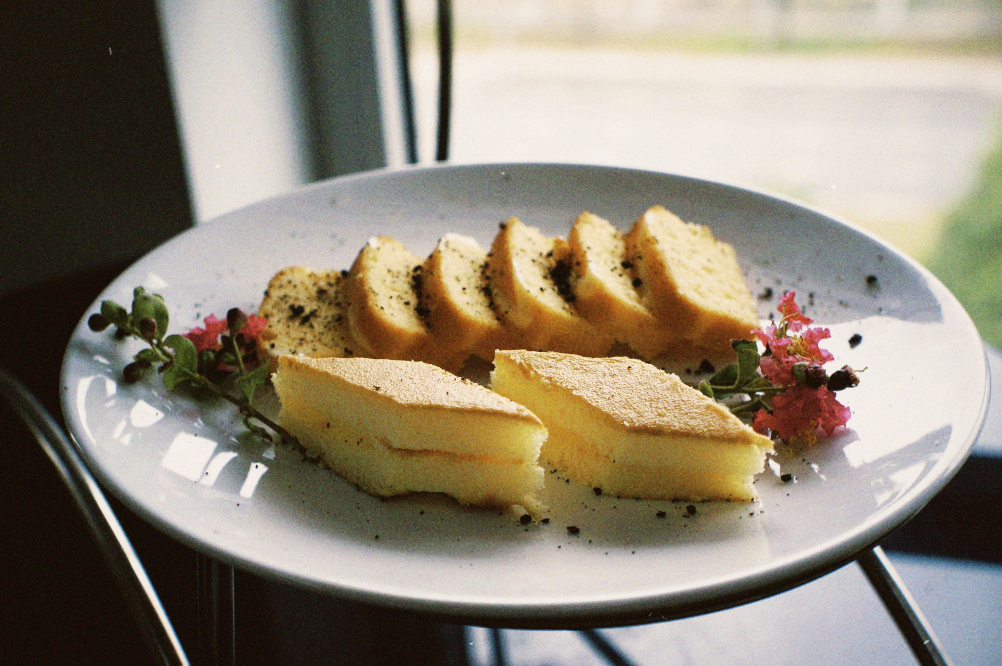 Overhead view of cake slice on black plate with gold fork, garnished with edible flowers