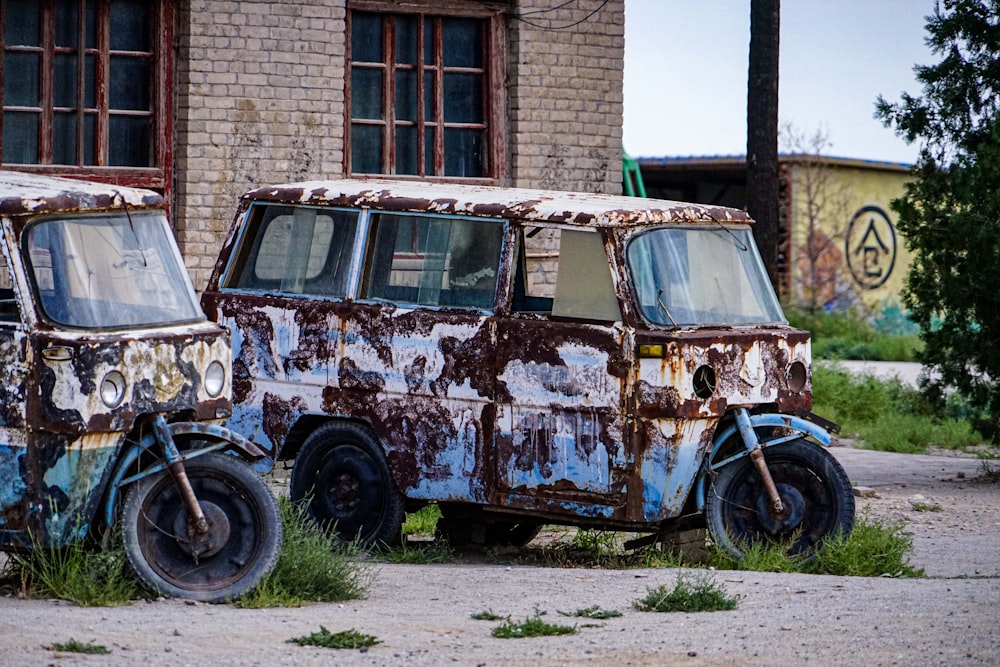 two old rusted out vans sitting in a field