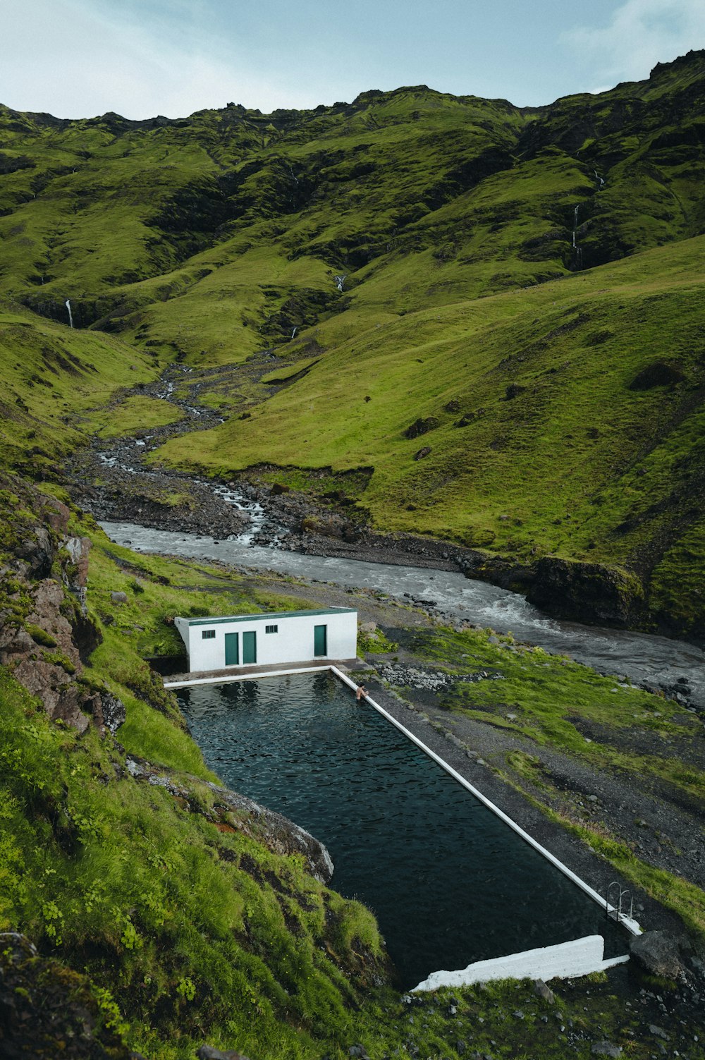 a small white house sitting on top of a lush green hillside