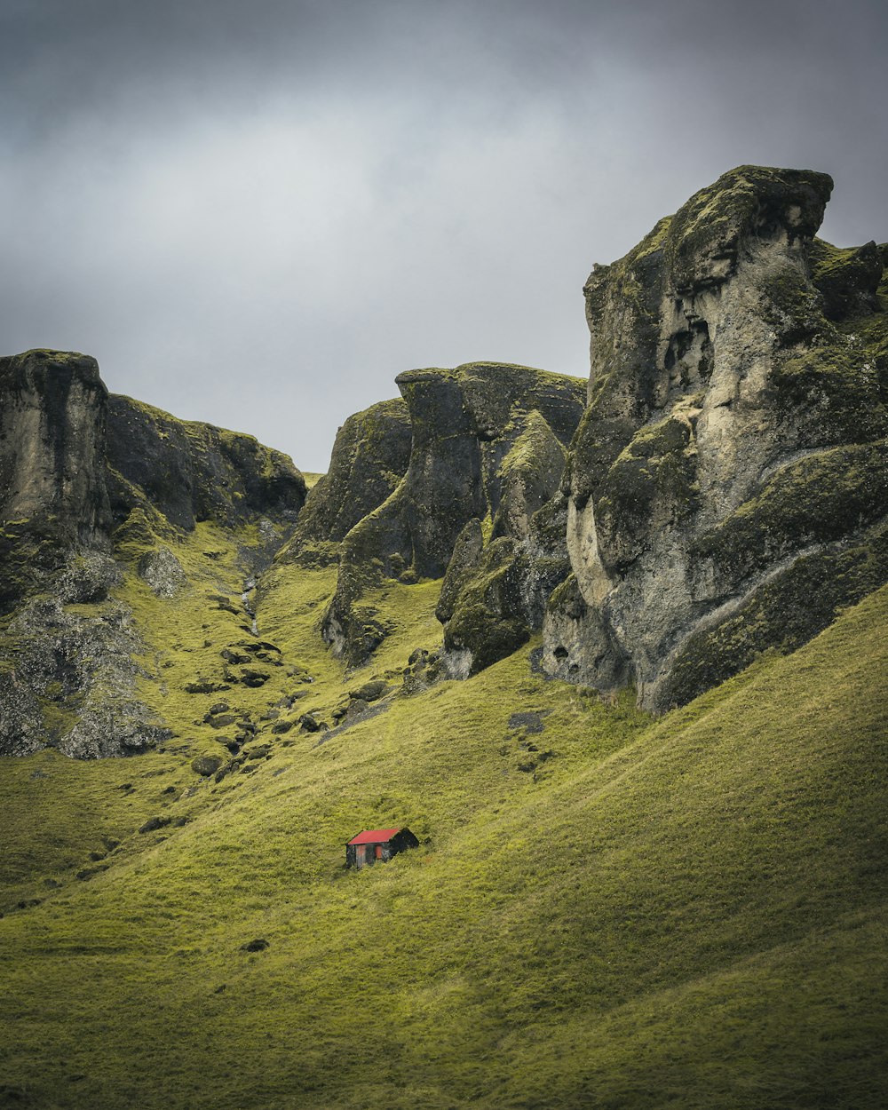 a lone red house on a grassy hill