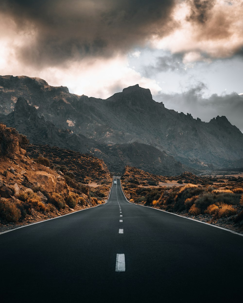 a long straight road with a mountain in the background