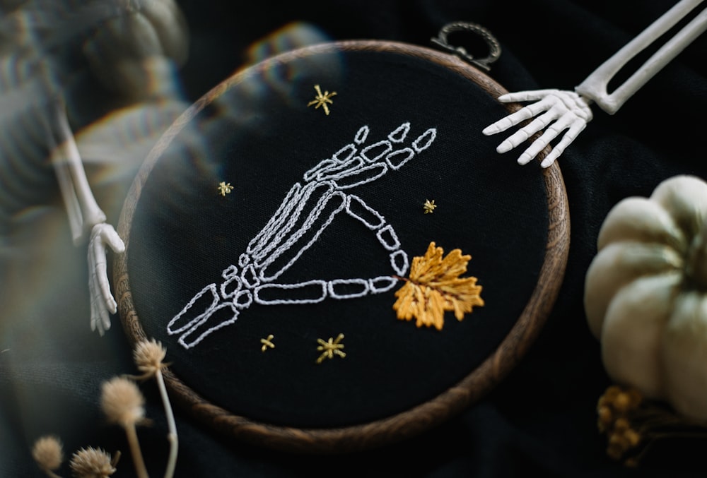 a hand embroidered picture of a skeleton holding a pumpkin