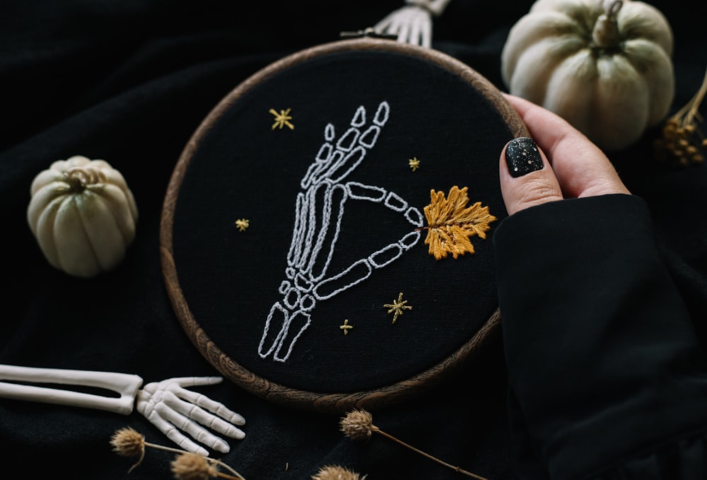 a person holding a hand embroideryed picture of a skeleton