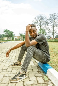 Casual pants styled with a relaxed shirt and sneakers, set in a sunny outdoor park setting with greenery.