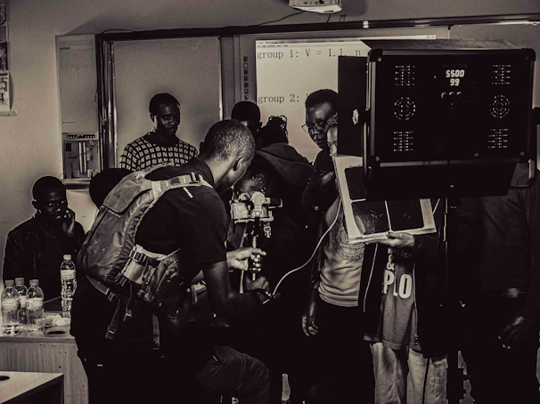 Close-up of a camera setup on a film set with students adjusting lighting and audio equipment.