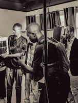 A group of people are in a room with professional camera equipment, engaged in what appears to be a filming or photography session. Various individuals hold cameras and other gear, focusing intently on their work.