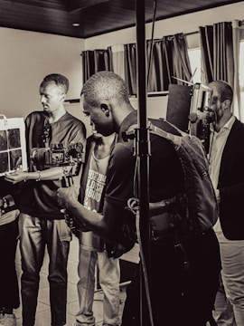 A group of people are in a room with professional camera equipment, engaged in what appears to be a filming or photography session. Various individuals hold cameras and other gear, focusing intently on their work.