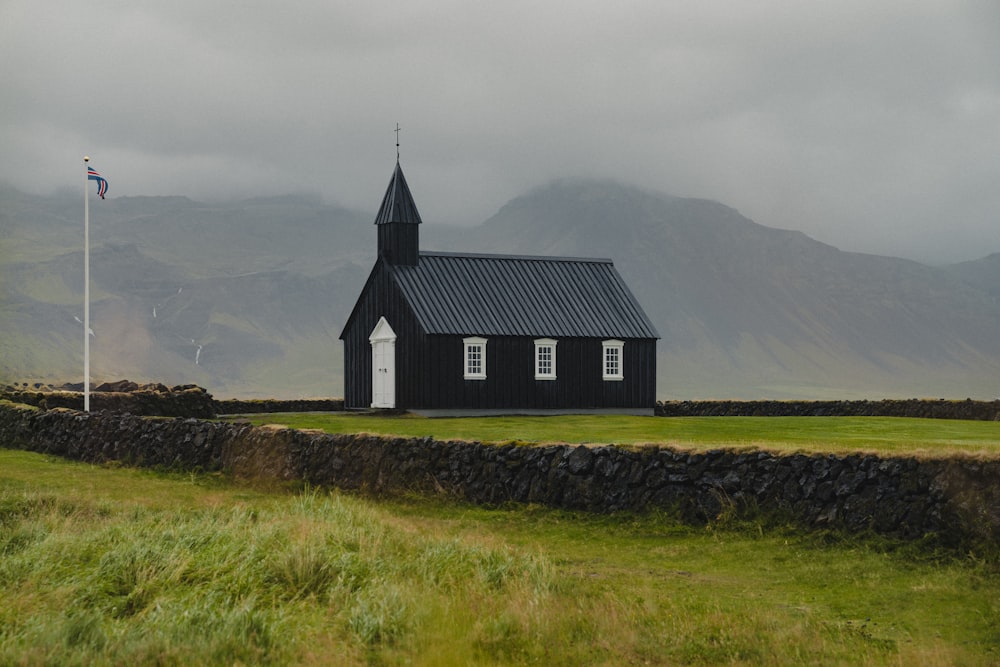 uma pequena igreja preta com um campanário em um campo gramado