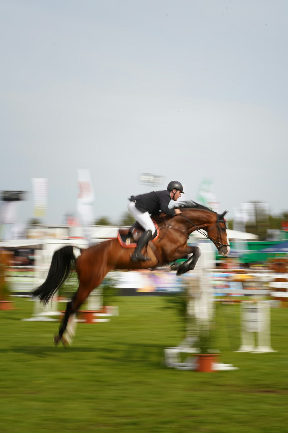 a man riding a brown horse over an obstacle