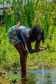 Volunteers measuring water quality in a rural village under bright daylight.