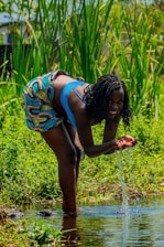 A researcher in the field collecting water samples from a rural stream.