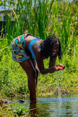 A technician collecting a water sample from a residential well on a sunny day.