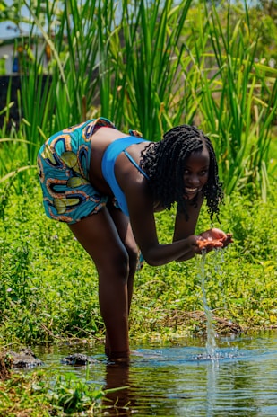 A researcher in the field collecting water samples from a rural stream.