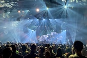 A panoramic view of a massive crowd enjoying a live concert with illuminated stage.