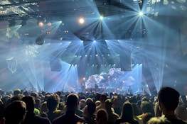 A panoramic view of a massive crowd enjoying a live concert with illuminated stage.