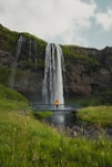 a person standing on a bridge in front of a waterfall