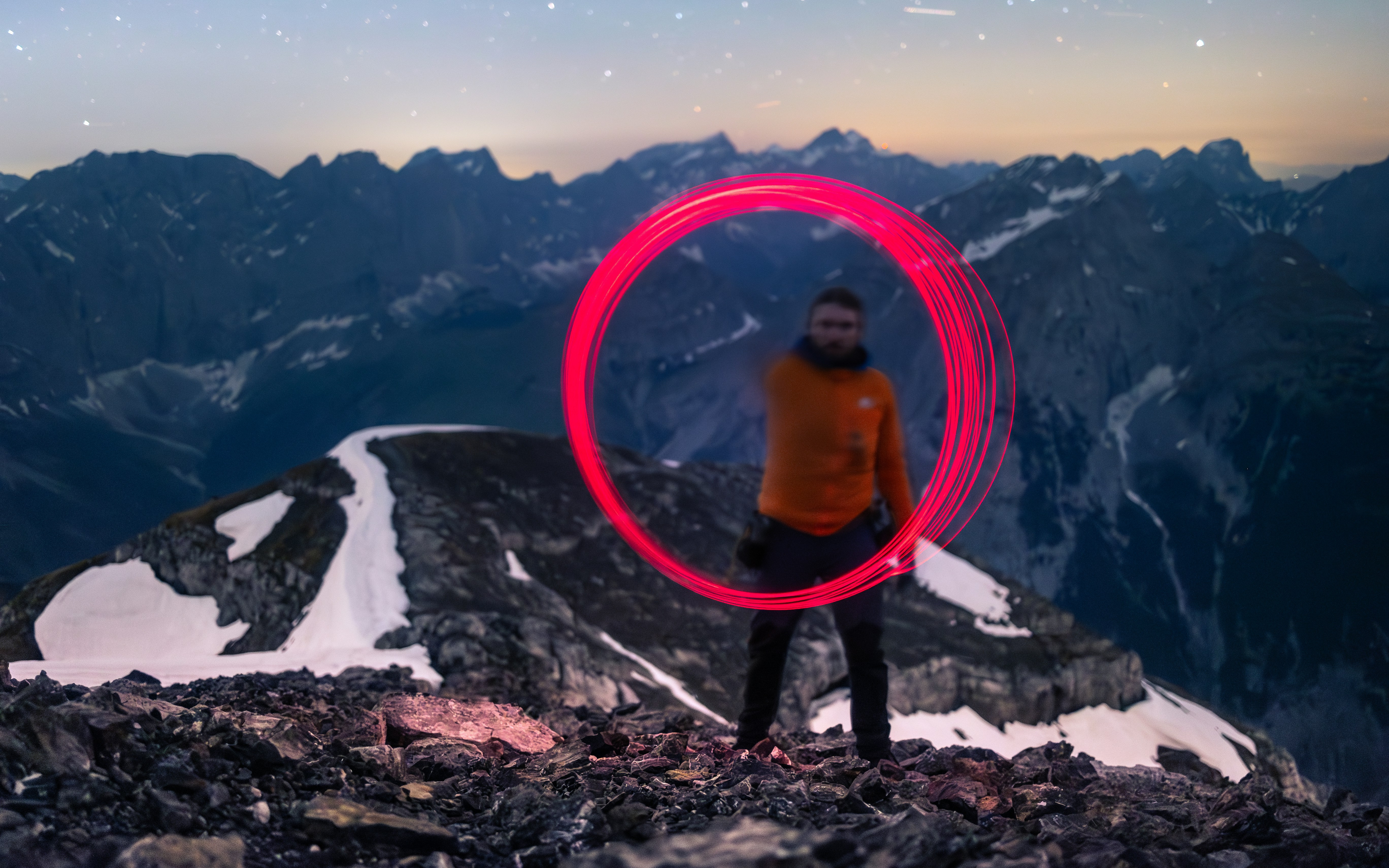 a man standing on top of a mountain holding a red circle