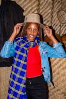 A woman adjusting a vibrant coral scarf before a café window on a crisp day.