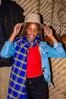 A woman adjusting a vibrant coral scarf before a café window on a crisp day.