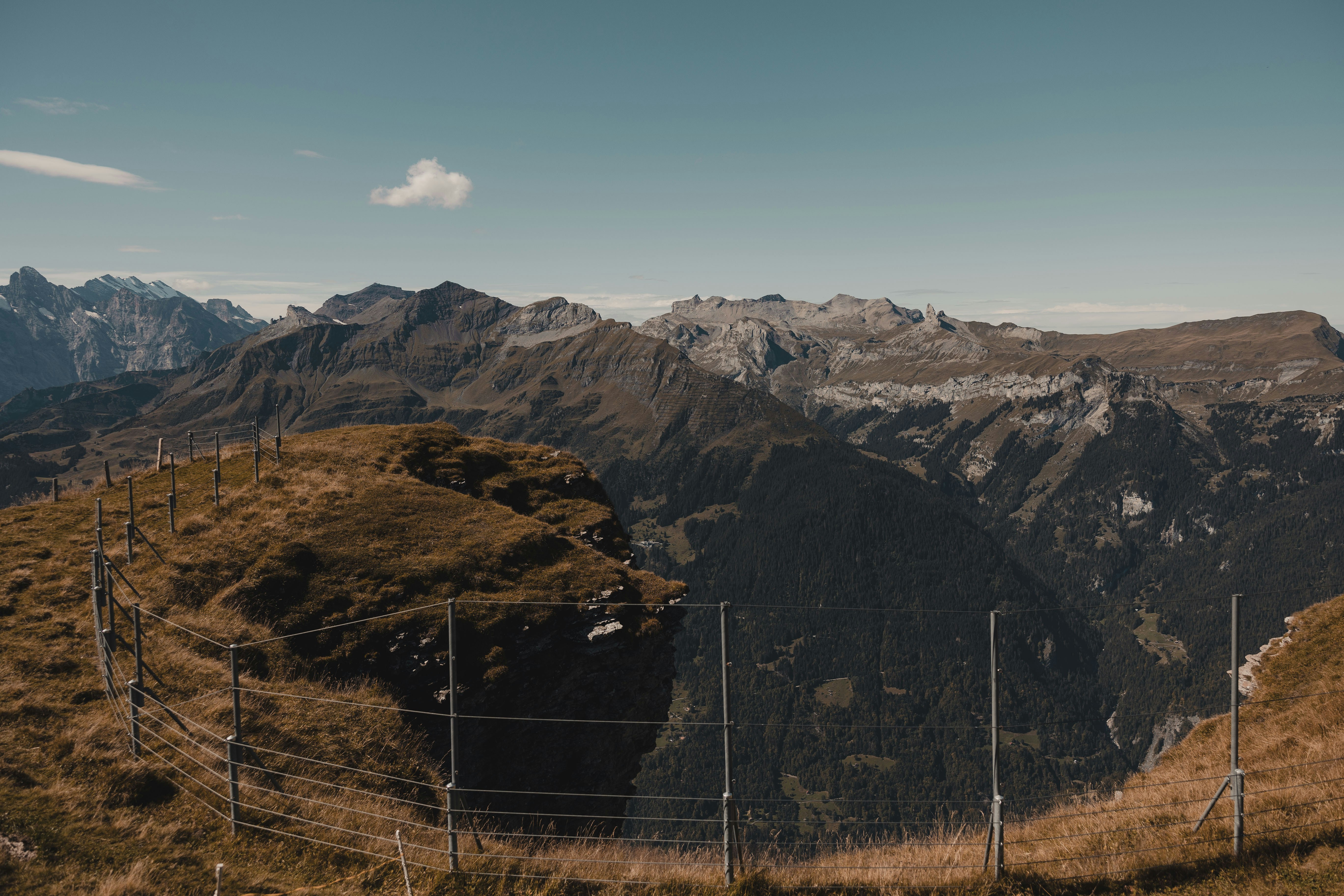 a view of a mountain range with a fence in the foreground