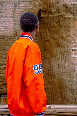 A model wearing a bright orange sports jacket with sleek modern lines.
