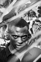 Black and white portrait of Nguxi dos Santos filming in an Angolan village.