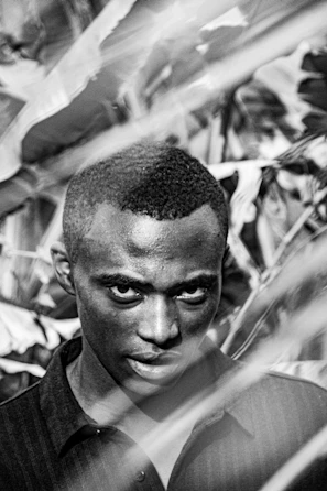 Black and white portrait of Nguxi dos Santos filming in an Angolan village.