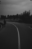 A moody black and white capture of a lone traveler walking along a deserted path.