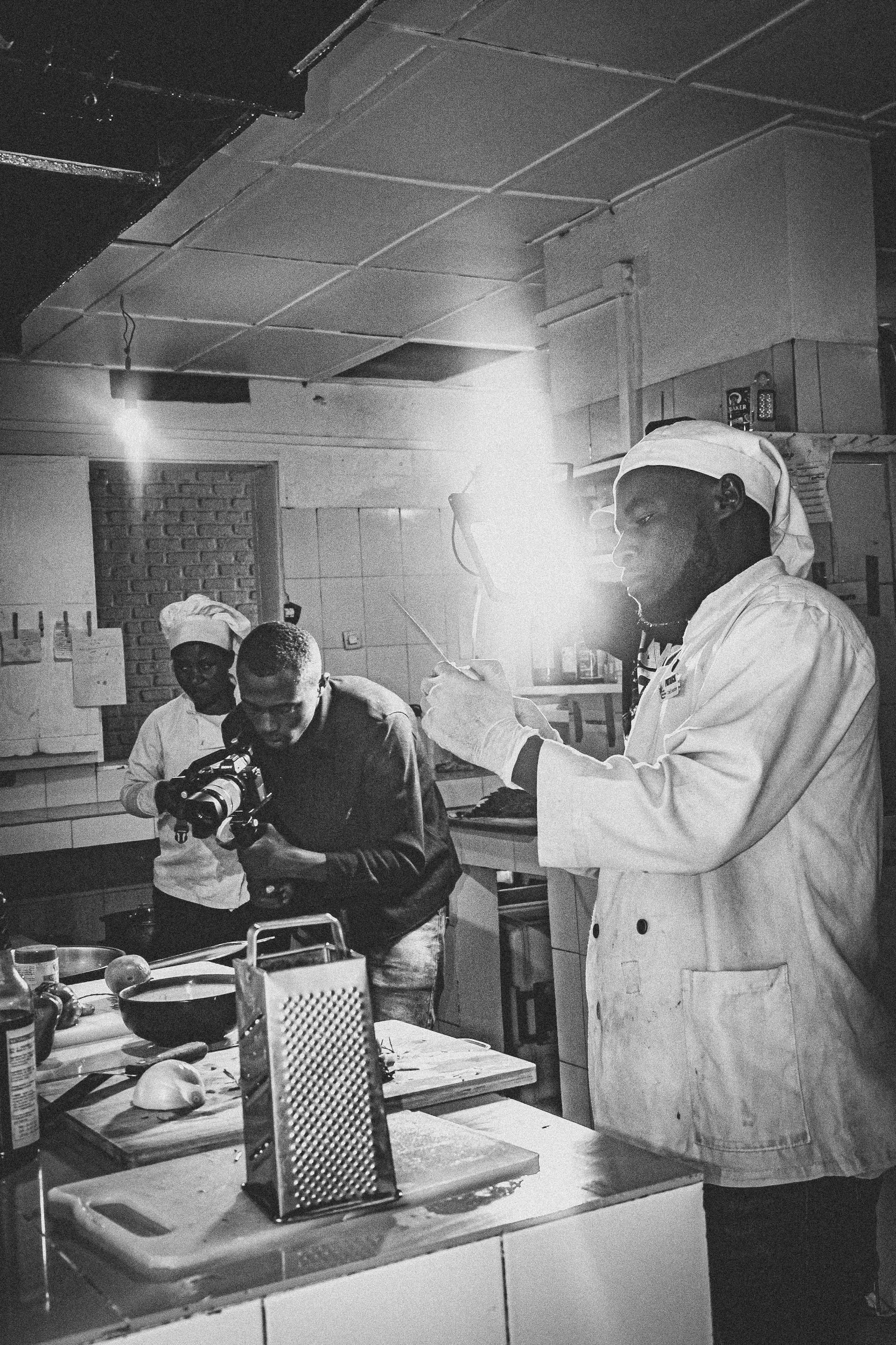A dynamic behind-the-scenes photo of Jesús “Chuy” Cervantes filming a chef preparing a signature dish in a cozy, stylish kitchen.