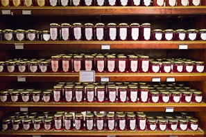 Colorful jars of homemade jams and preserves lined up on a kitchen counter.