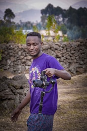 A dynamic photo of a male sports influencer filming content outdoors with a camera, wearing sporty attire in purple and light green accents.