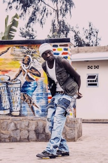 Binda posing with a guitar against a colorful urban mural.
