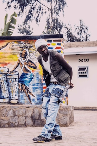 Binda posing with a guitar against a colorful urban mural.