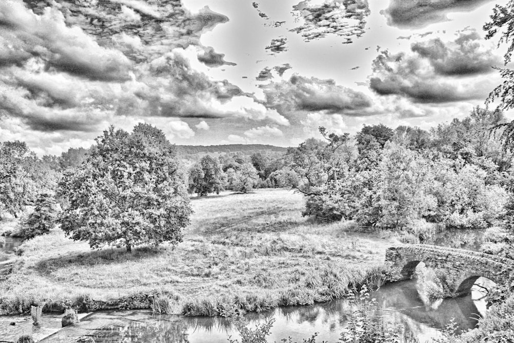 a black and white photo of a river and a bridge