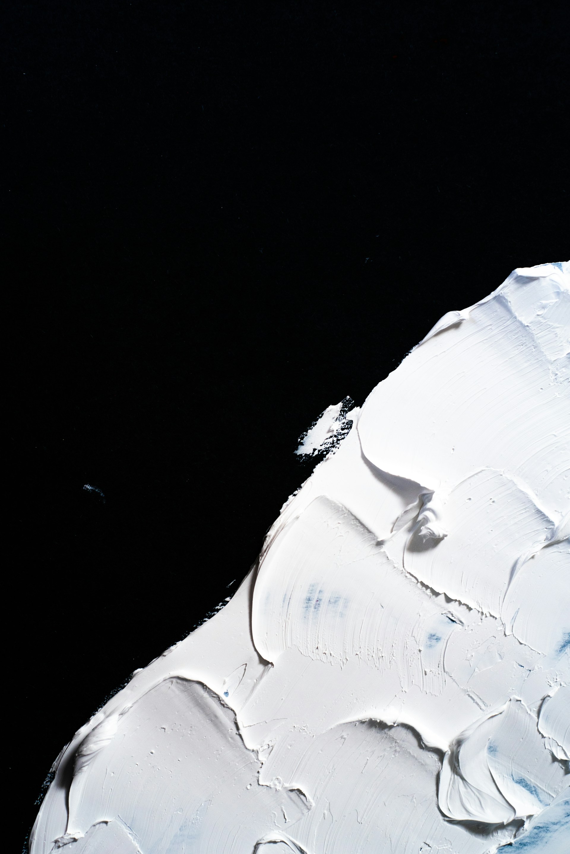 A close-up of textured canvas showing layered black paint creating depth and movement in a modern composition.