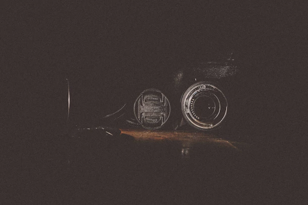 A sleek black and gold camera lens capturing a dramatic food close-up in a dark studio setting.