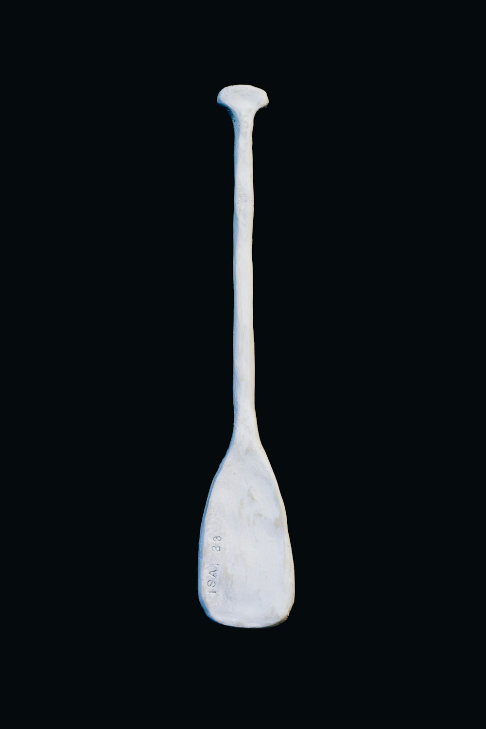 a white spoon with a long handle on a black background