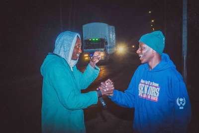 A friendly insurance agent shaking hands with a truck driver beside a big rig.