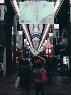 A bustling shopping corridor inside St James with shoppers carrying bags and bright store displays.