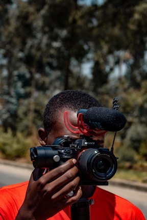 A news reporter holding a microphone with a GPS tracking screen in the background.