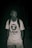 A person stands in a dark environment, wearing a white t-shirt with the Aape logo, a backpack, and light-colored shorts. The background is dimly lit, suggesting it might be nighttime or in a low-light setting.