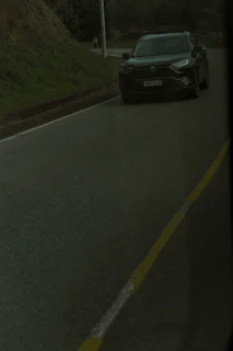 Side view of a dark navy BMW SUV driving on a mountain road.