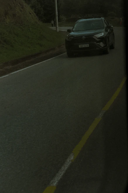 Side view of a dark navy BMW SUV driving on a mountain road.
