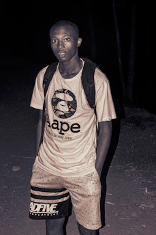 Close-up of a young Indian man confidently wearing a bold graphic tee from Rudrawears under neon city lights at night.