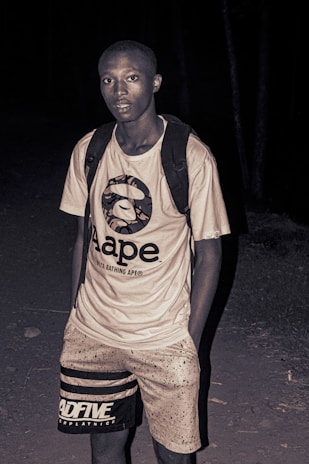 Editorial style shot of a male model in a crisp white t-shirt and black cap, highlighting the brand’s modern typography.