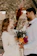 Bride and groom sharing a joyful moment under a floral arch at an outdoor wedding.
