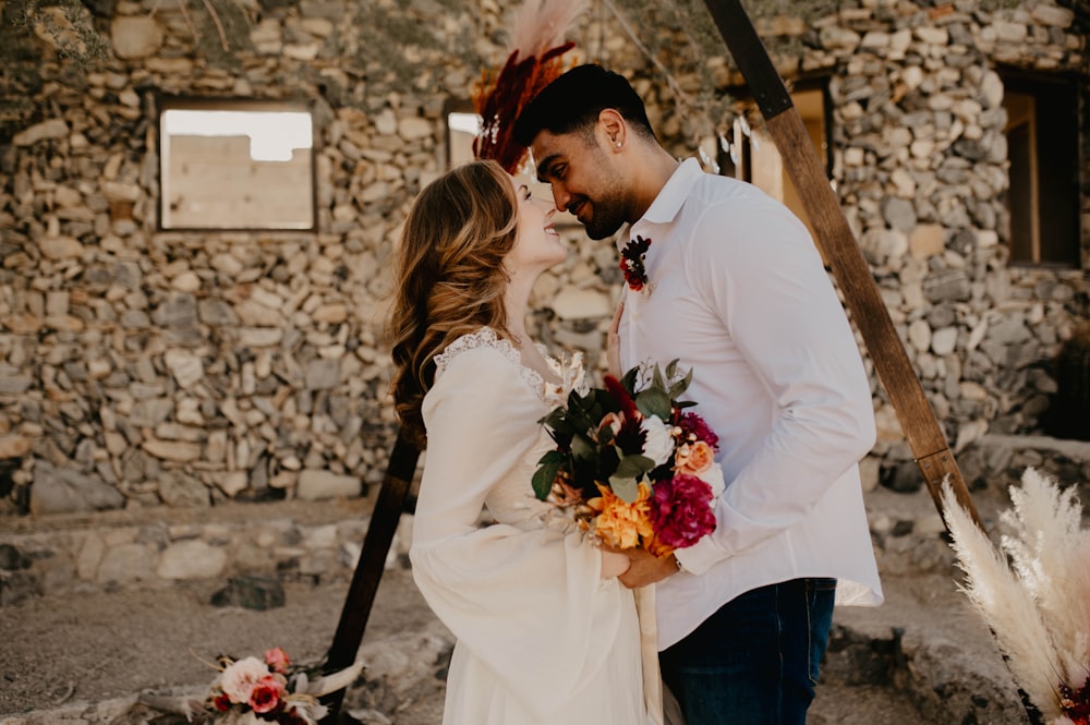 a bride and groom kissing in front of a stone building